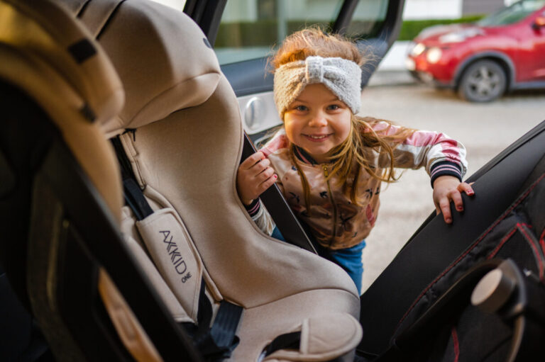 girl using the easy climb handle on an Axkid One rear-facing car seat